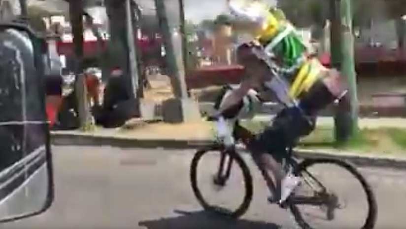 Un ciclista con una gran imagen de San Judas en las espaldas sufre bochornoso accidente (VIDEO)