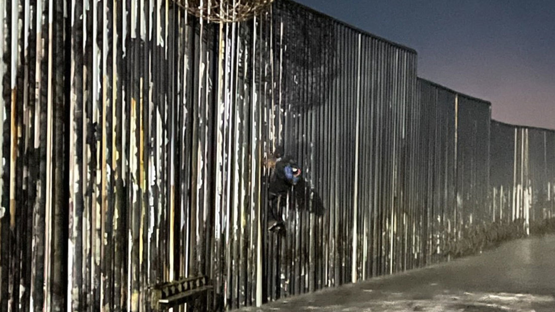 Agentes de EE.UU. rescatan a un migrante mexicano colgado del muro fronterizo, donde se adentra en el océano