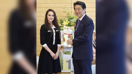 Alina Zagitova (L) presents a soft toy of her pet Masaru to Japan's Prime Minister Shinzo Abe (R) © AFP / JIJI PRESS