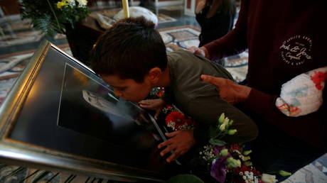 A child kisses a picture of late Metropolitan Amfilohije Radovic. Podgorica, Montenegro, October 30, 2020 © REUTERS/Stevo Vasiljevic