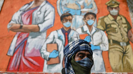A man looks on as he walks past a mural based on Covid-19 coronavirus safety protocols on the walls of an underpass during an ongoing weekend curfew imposed in New Delhi on January 16, 2022 to curb the spread of the Covid-19 coronavirus. © Sajjad HUSSAIN / AFP
