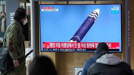 Люди смотрят экран телевизора, показывающий программу новостей, сообщающую об испытании межконтинентальной баллистической ракеты Северной Кореи на вокзале в Сеуле.  © AP / Ли Джинман