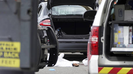 A body lays covered in the parking lot of a supermarket in Buffalo, N.Y., on May 14, 2022.