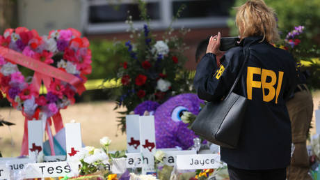 An FBI agent is shown on Friday taking a picture of a memorial for victims of Tuesday's mass shooting at Robb Elementary School in Uvalde, Texas.