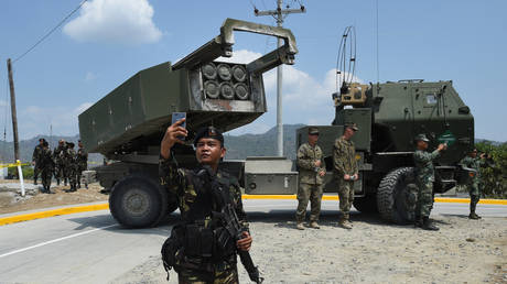 FILE PHOTO. A Philippine soldier takes a selfie in front of an M142 High Mobility Artillery Rocket System (HIMARS). ©TED ALJIBE / AFP
