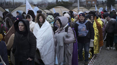 FILE PHOTO. Refugees wait in a crowd for transportation after fleeing Ukraine and arriving at the border crossing in Medyka, Poland. © AP Photo/Markus Schreiber