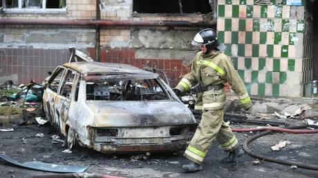 A firefighter walks past a destroyed car in Donetsk on June 13, 2022.