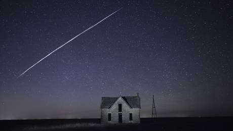FILE PHOTO: A long exposure photo shows a string of SpaceX Starlink satellites passing over an old house near Florence, Kansas.