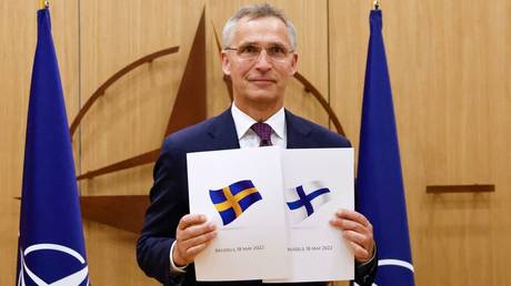 NATO Secretary-General Jens Stoltenberg poses with application documents presented by Finland and Sweden. © AFP / Johanna Geron