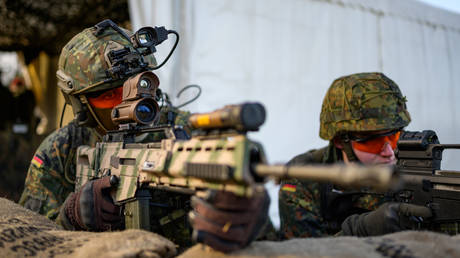 Soldiers of the Bundeswehr squat with the G36 A2 assault rifle during a demonstration in a position. © Philipp Schulze / picture alliance via Getty Images