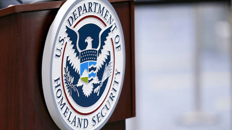 ФОТОГРАФИЯ: Табличка Министерства внутренней безопасности США выставлена ​​на подиуме в международном аэропорту Майами во Флориде.