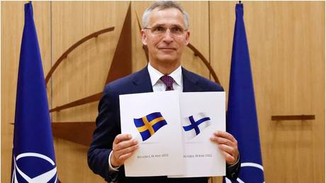 NATO Secretary General Jens Stoltenberg poses with documents presented by envoys of Sweden and Finland, May 2022. © Johanna Geron / AFP
