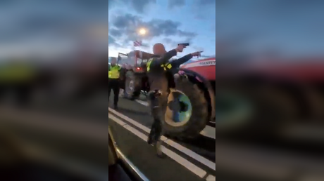 A police officer aims his weapon at a tractor driver while issuing orders during a protest in Heerenveen, Netherlands, July 5, 2022.