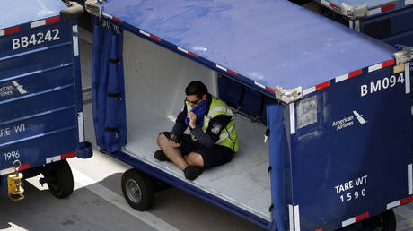 FILE PHOTO. A crew member sits in a luggage cart at Sky Harbor International Airport to avoid the heat, in Phoenix. June 20, 2017.