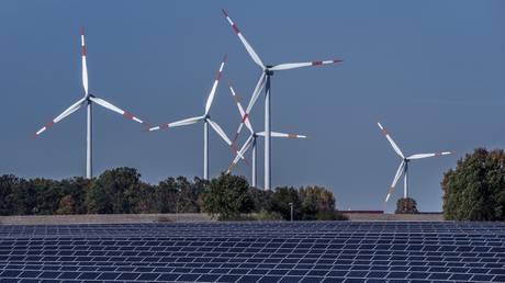 FILE PHOTO: Wind turbines turn behind a solar farm in Rapshagen, Germany, Thursday, Oct. 28, 2021