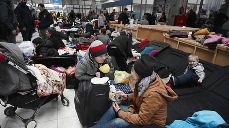 FILE PHOTO: People sit on camp beds in a refugee reception center at the Ukrainian-Polish border crossing in Korczowa, Poland, March 5, 2022 © AFP / Olivier Douliery