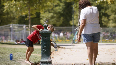 FILE PHOTO. A child fills up a bottle at a water fountain in the Champ de Mars park, near the Eiffel Tower in Paris.