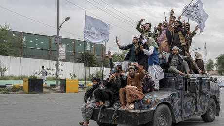 Taliban fighters hold weapons as they ride on humvee to celebrate their victory day near the US embassy in Kabul on August 15, 2022.