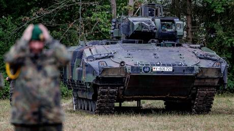 A German soldier stands in front of an armored personnel carrier. © AFP / Axel Heimken