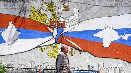 A Kosovo Serb man walks next to a graffiti showing the map of Kosovo in a Serbian flag, on a street in the majority ethnic-Serb northern part of the city of Mitrovica. © Armend NIMANI / AFP