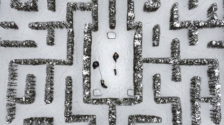 FILE PHOTO: People walk with their dogs through a snow-covered garden maze in Gelsenkirchen, Germany, Wednesday, Feb. 10, 2021