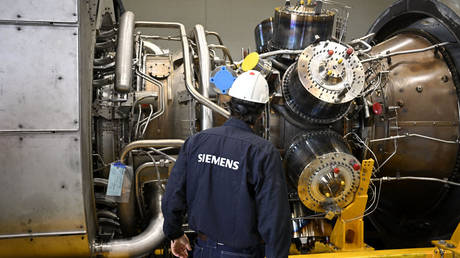An employee of Siemens Energy stands in front of a turbine of the Nord Stream 1 pipeline at the plant of Siemens Energy in Muelheim an der Ruhr.