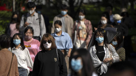 Commuters wearing face masks walk along a street in the central business district in Beijing, China, September 8, 2022