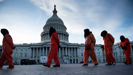 Demonstrators dressed in Guantanamo Bay prisoner uniforms march past Capitol Hill in Washington, DC.