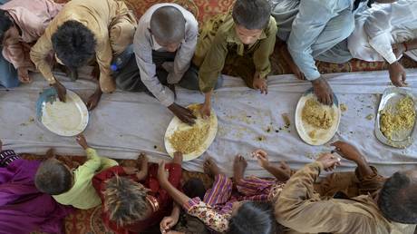 FILE PHOTO: Children eat food provided by an aid group in a flood-hit district of Baluchistan province, Pakistan, September 15, 2022.