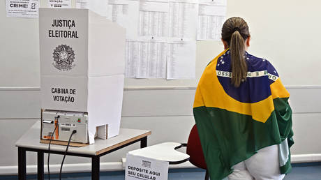 A woman wrapped in a Brazilian flag votes at a polling station during the legislative and presidential election, in Brasilia, Brazil, on October 2, 2022.