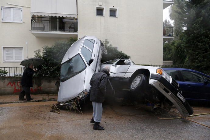 People look at damaged cars following heavy rain in Chalandri suburb north of Athens February 22, 2013. (Reuters/John Kolesidis)