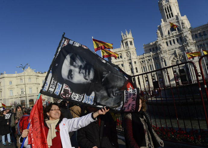 A woman holds a flag depicting a picture of Argentine-born Cuban revolution hero Che Guevara during a protest by public workers, small political parties and non-profit organisations against government austerity on February 23, 2013 in Madrid. (AFP Photo / Pierre-Pholippe Marcou)