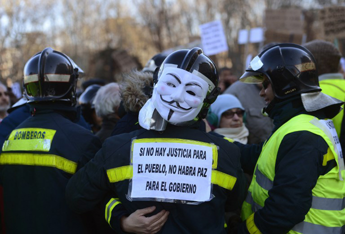 A firefighter wearing a Guy Fawkes mask and holding a placard reading "If there is no justice for the people, there will be no peace for the government" attends a demonstration on February 23, 2013 in Madrid. (AFP Photo / Pierre-Pholippe Marcou)