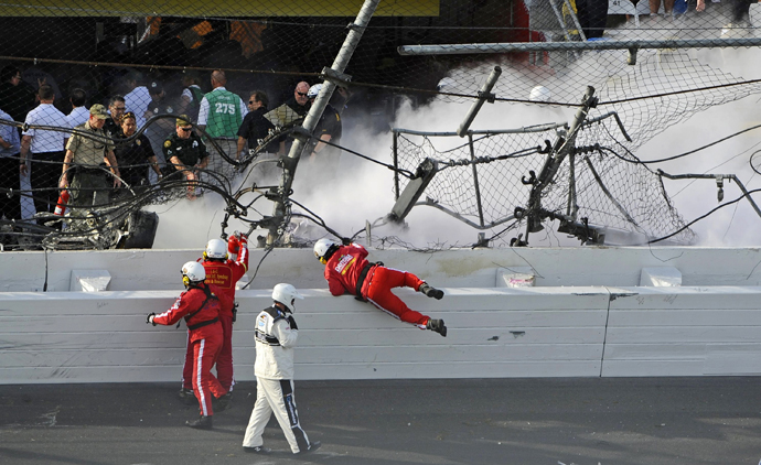 Rescue workers stand next to a hole in the catch fence following a last-lap incident. (Reuters)