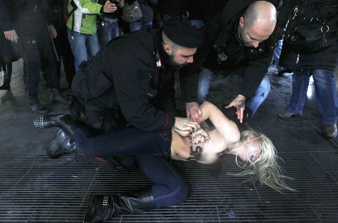 Police stop an activist from the women's rights organisation Femen during a protest outside the polling station where former Prime Minister Silvio Berlusconi cast his vote in Milan, February 24, 2013. (Reuters/Cezaro De Luca) 