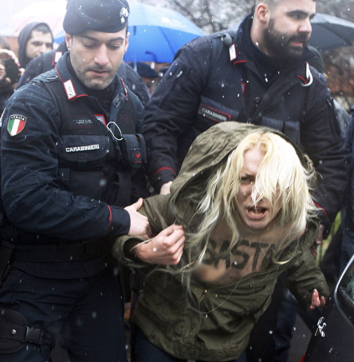 Carabinieri stop an activist from the women's rights organisation Femen during a protest outside the polling station where former Prime Minister Silvio Berlusconi cast his vote in Milan, February 24, 2013. (Reuters/Cezaro De Luca)