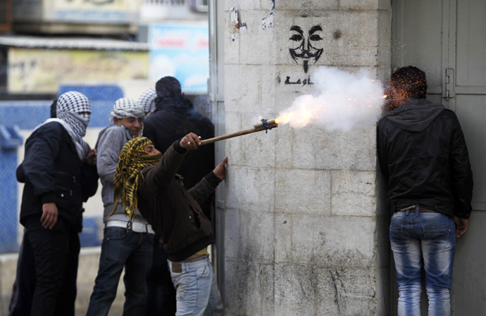 A Palestinian protester uses a makeshift launcher to shoot fire crackers as another protester takes cover during clashes with Israeli soldiers and border policemen in the West Bank city of Hebron February 24, 2013.(Reuters / Ammar Awad)