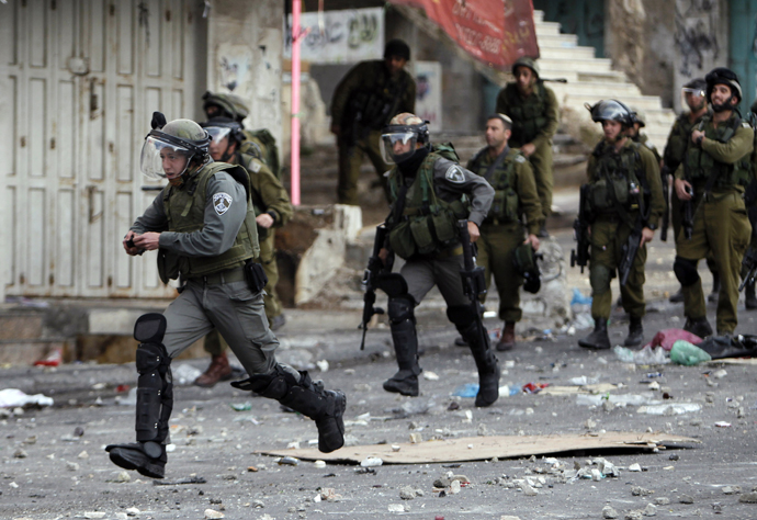 An Israeli border policeman holds a stun grenade as he runs during clashes with stone-throwing Palestinian protesters in the West Bank city of Hebron February 25, 2013. (Reuters / Ammar Awad)
