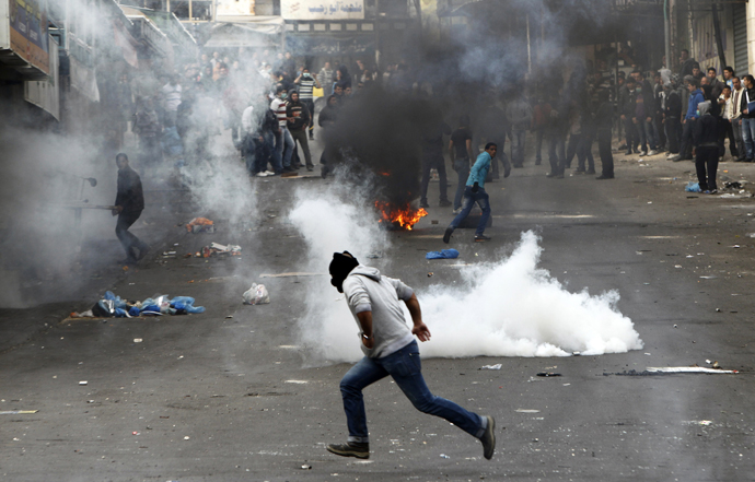 A stone-throwing Palestinian protester runs past tear gas fired by Israeli soldiers during clashes in the West Bank city of Hebron February 25, 2013. (Reuters / Ammar Awad)