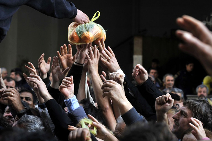 People reach out for a bag of oranges during a free distribution of fruit and vegetables by Greek farmers in Athens. (AFP Photo / Louisa Gouliamaki)