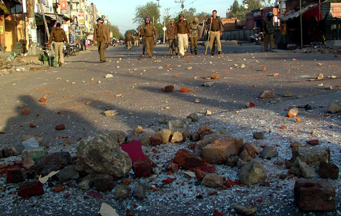 Indian police patrol along a street strewn with rocks after youth hurled stones at buses and police outside a hospital in a low-income area of New Delhi on March 1, 2013. (AFP Photo)