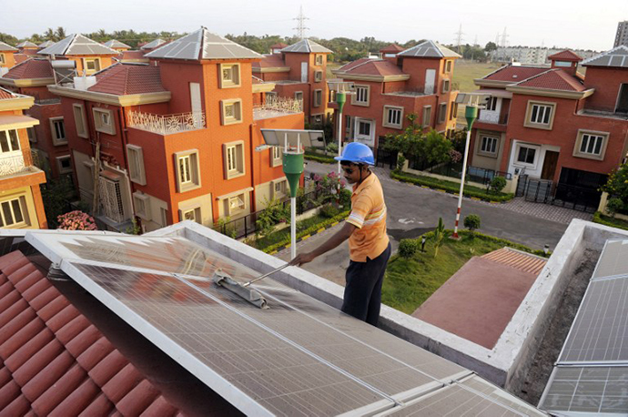 An Indian worker cleans solar panels fitted onto the roof of a residential house in Rabirashmi Abasan, a solar housing complex at Rajarhat close to Kolkata. (AFP Photo / Deshakalyan Chowdhury)