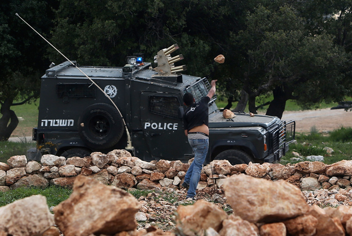 A Palestinian protester throws stones at an Israel border police jeep during a protest marking the 8th anniversary of their campaign against the controversial Israeli barrier in the West Bank village of Bilin near Ramallah March 1, 2013 (Reuters / Mohamad Torokman)