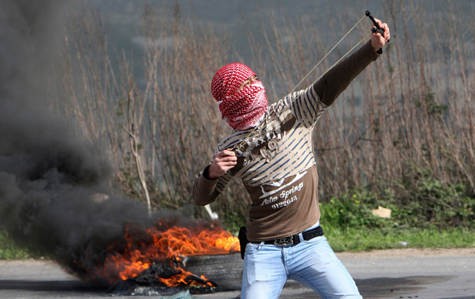 A Palestinian protester uses a sling shot to throw stones towards Israeli forces during clashes at Hawara checkpoint near the West Bank city of Nablus March 1, 2013 (Reuters / Abed Omar Qusini)