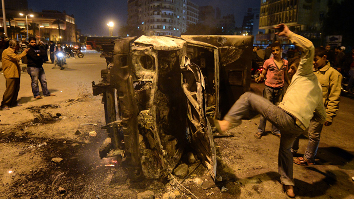 An Egyptian man gives a kick towards a police vehicle that has been burnt by angry protesters following clashes with plainclothes policemen in Cairoâs on Tahrir square on March 3, 2013 (AFP Photo / Khaled Desouki)
