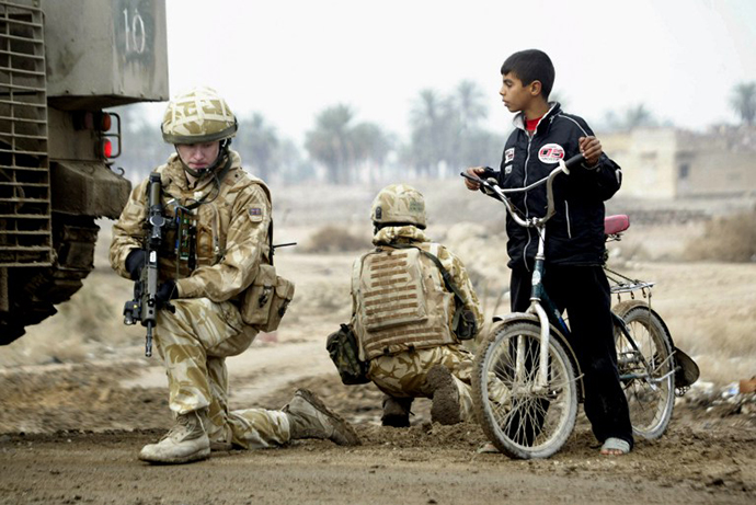 An Iraqi boy stops his bicycle next to British soldiers as they secure the area at the site where a roadside bomb targeted their patrol in the southern city of Basra, 21 January 2007. (AFP Photo / Essam Al-Sudani)