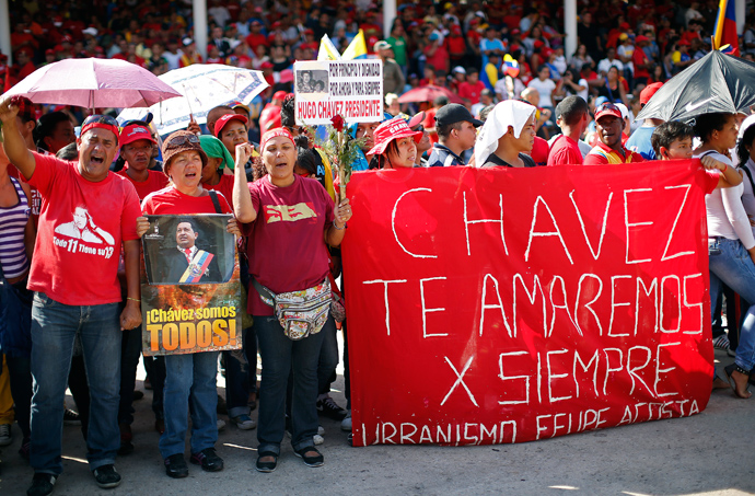 Supporters of late Venezuelan leader Hugo Chavez watch as his coffin arrives at the Military Academy, where his wake will be held, in Caracas March 6, 2013. The banner reads, "Chavez, we will love you forever." (Reuters / Jorge Silva)