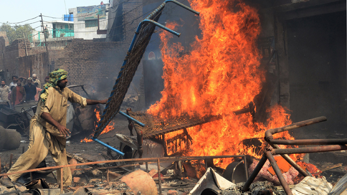 An angry Pakistani demonstrator torches Christian's belongings during a protest over a blasphemy row in a Christian neighborhood in Badami Bagh area of Lahore on March 9, 2013 (AFP Photo / Arif Ali)