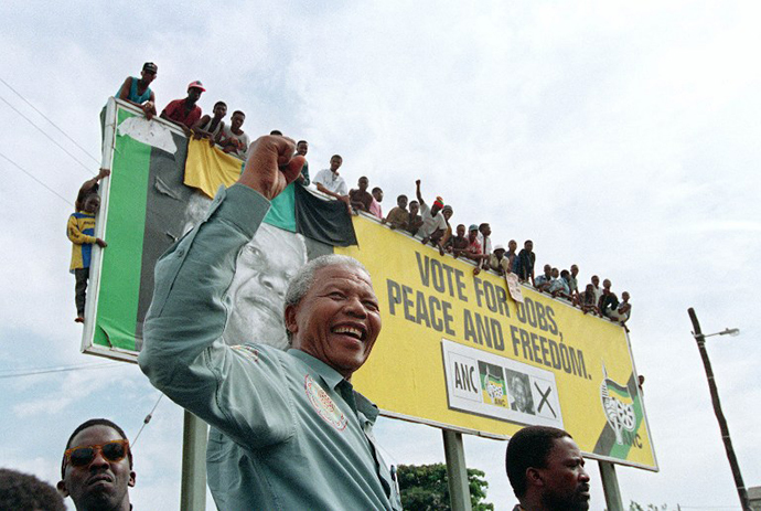 African National Congress (ANC) President Nelson Mandela greets young supporters who wait for atop a billboard in a township outside Durban, 16 April 1994 prior to an election rally. (AFP Photo / Alexander Joe)