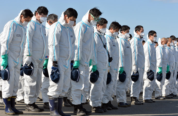 Police officers in radiation protection suits bow their heads to offer prayers in silence for tsunami victims in Namie, near the striken TEPCO's Fukushima Dai-ichi nuclear plant in Fukushima prefecture on March 11, 2013. (AFP Photo/Yoshikazu Tsuno)